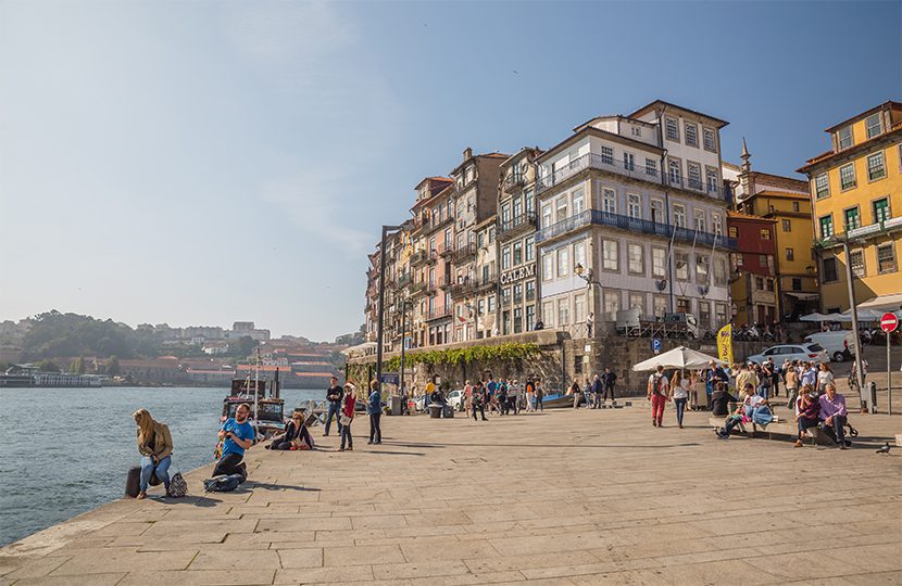 Turisti e locali si godono il sole lungo il fiume Douro