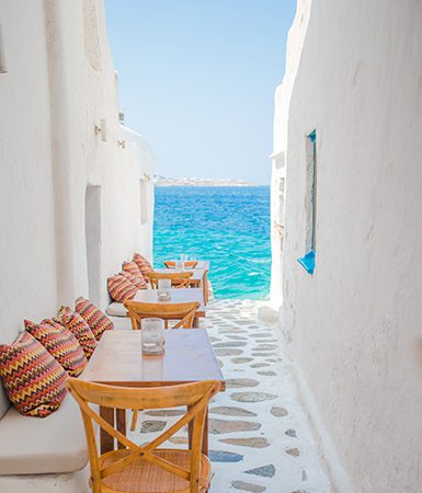 Benches with pillows in a typical Greek bar in Mykonos by TravnikovStudio