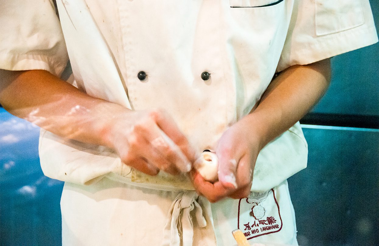 Chef wrapping xiaolongbao dumplings