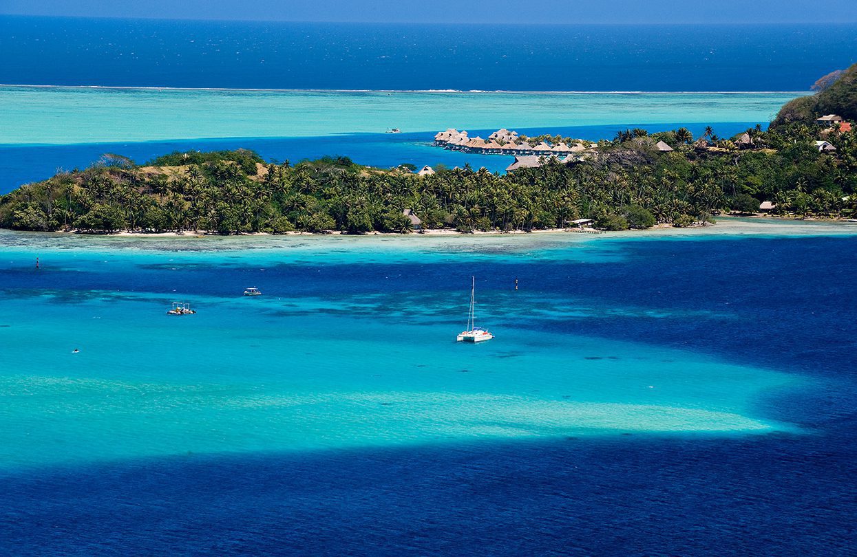 View over beautiful turquoise lagoon of bungalows, island and boats by Mark Skalny