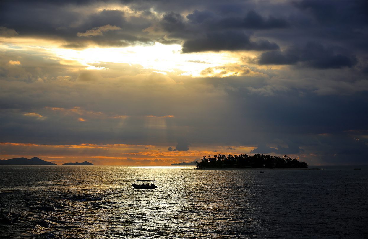 Boat travelling between Mamanucas islands at sunset, image by Tourism Fiji