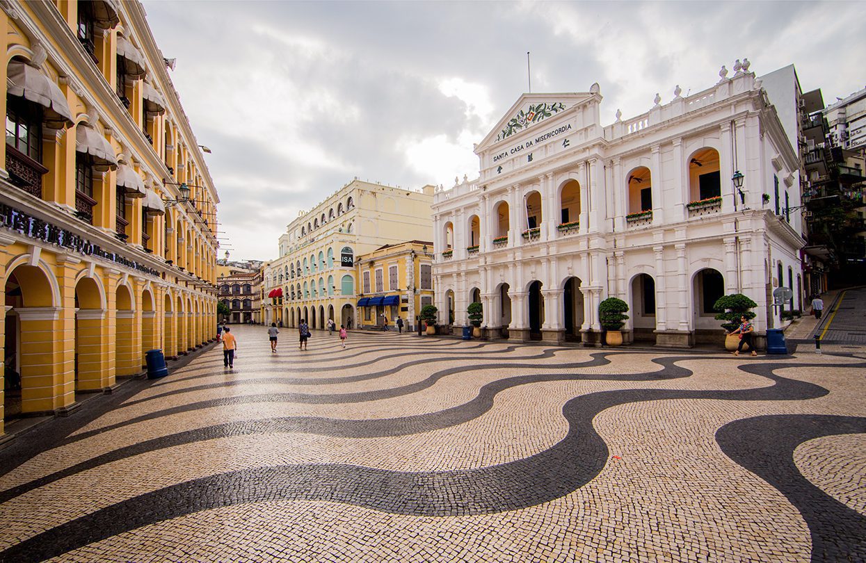 Senado Square is a paved public plaza surrounded by pastel-coloured European buildings in the middle of the area designated by UNESCO as the Historic Centre of Macau