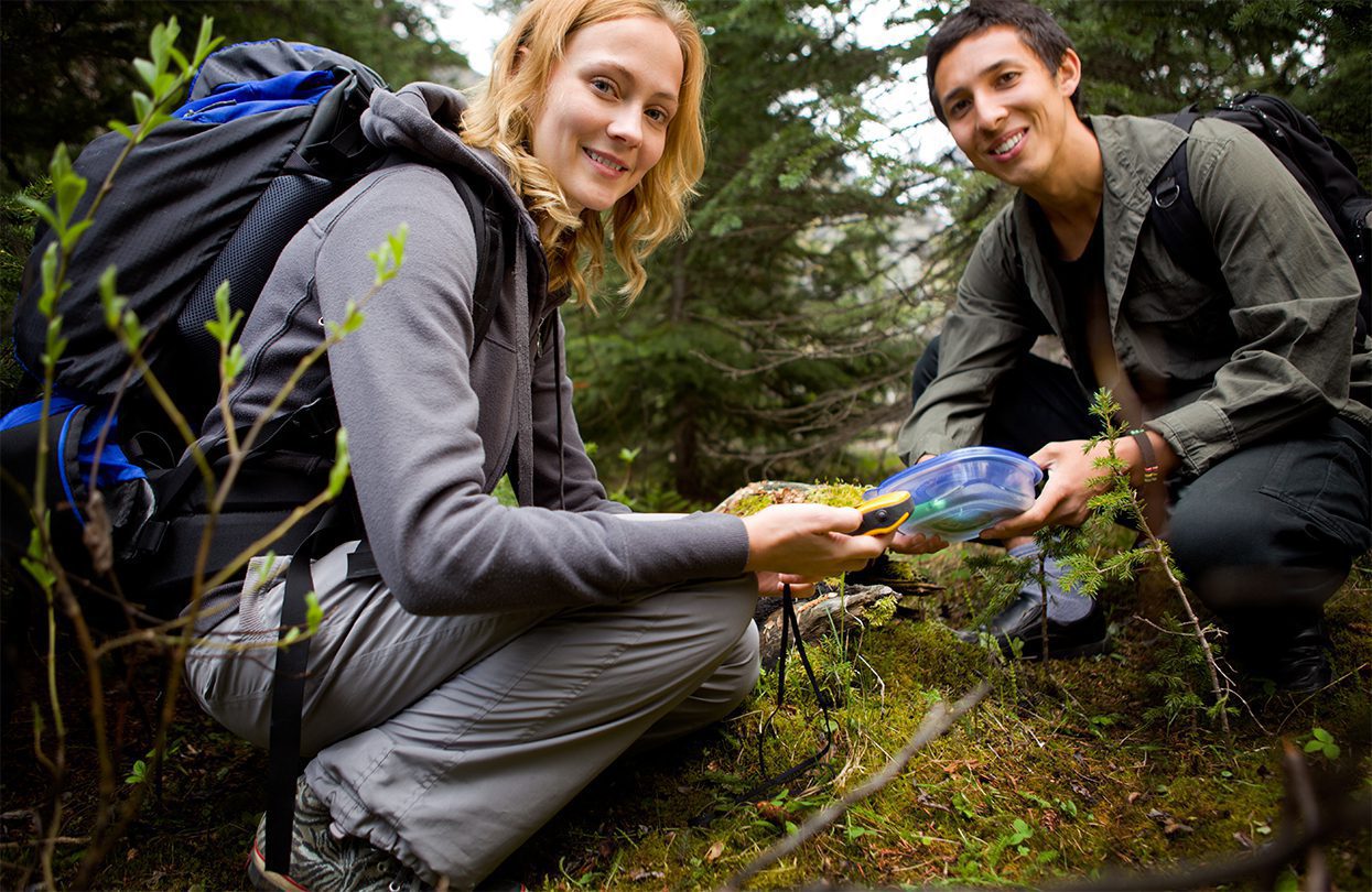 Finding a geocache in the forest using a GPS, photo by Tyler Olson