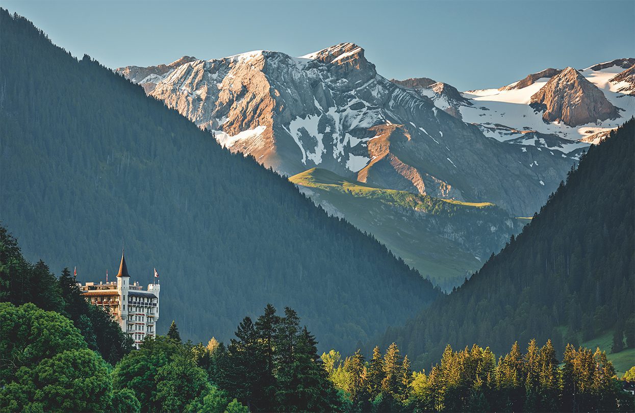 Alpine Gstaad’s exterior with the green landscape in the background
