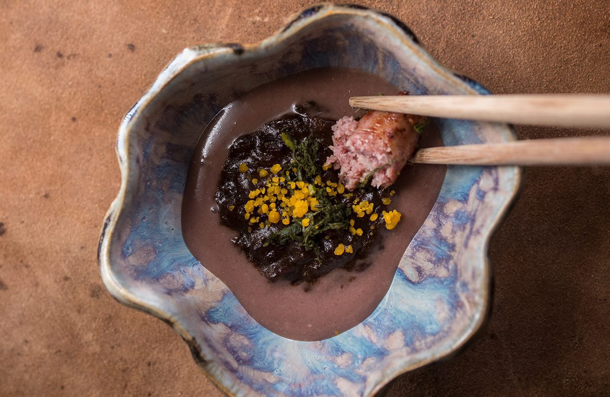 Dewakan black banana porridge uses heirloom rice mixed with banana served with cured egg, pickles and duck sausage
