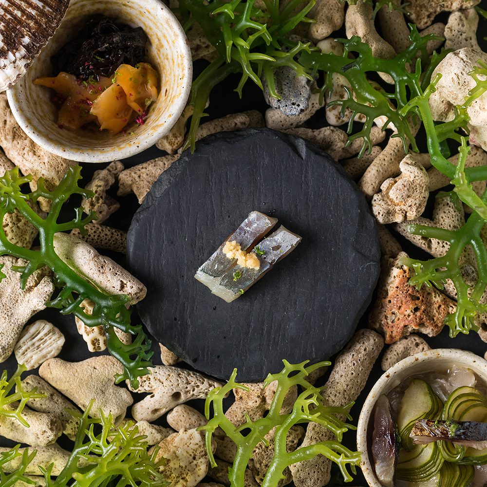 Toyo Eatery nilupak kamote (local sweet potato) sea urchin nata de coco, dalandan, grated cashew nuts, and a blue ternate petal, on top of a cassava crisp