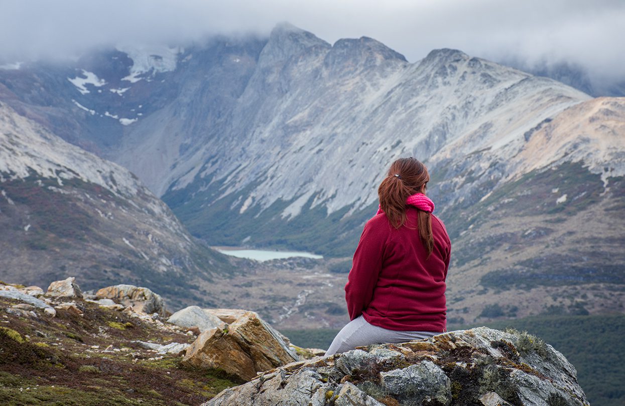 Young woman sitting on a stone in the mountain, image by Fabi Kop