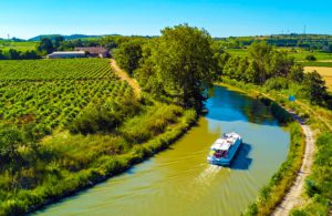Aerial top view of boat in Canal du Midi from above, family travel by barge and vacation in Southern France, photo by JaySi, shutterstock